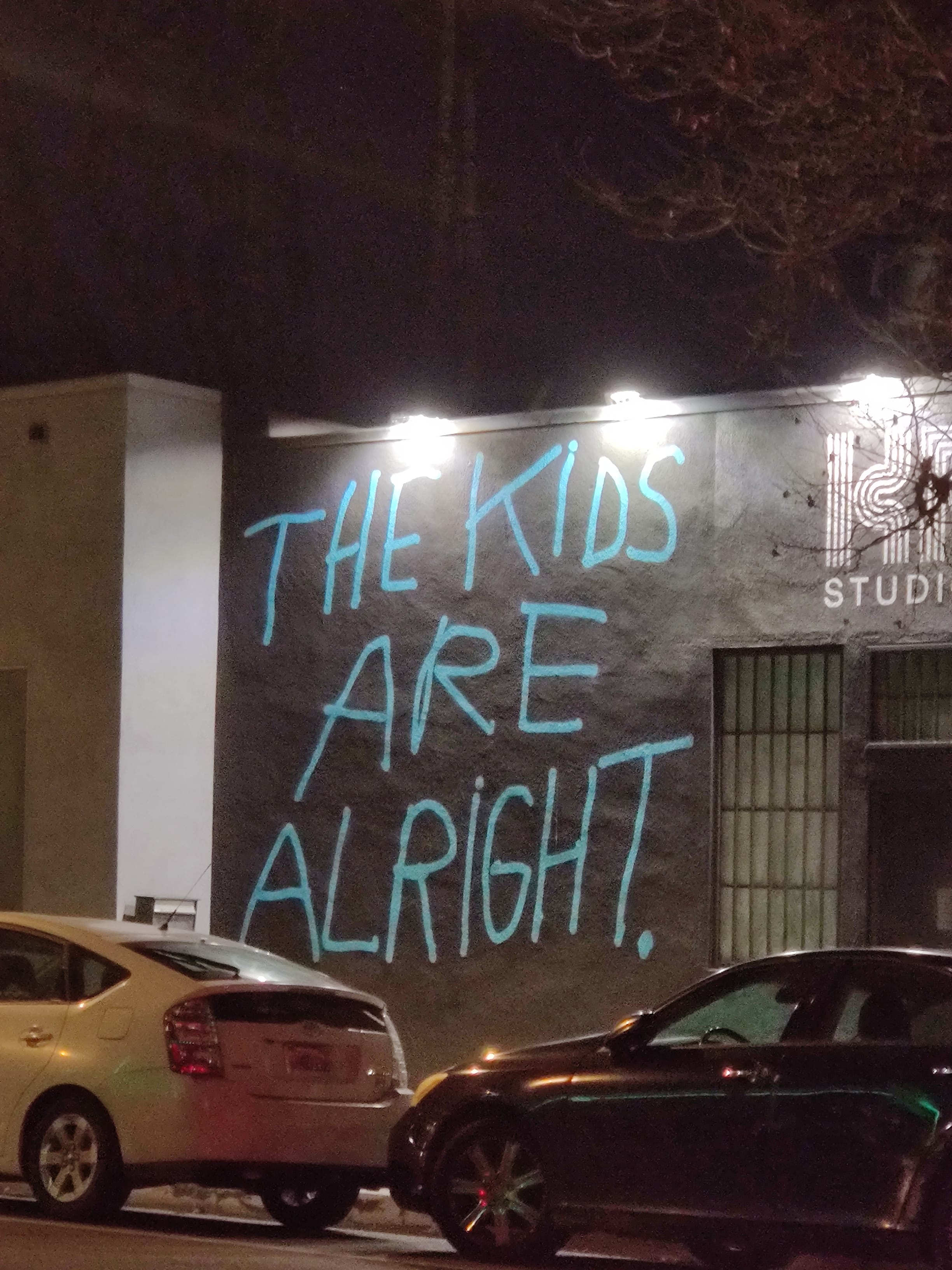 Chalk writing on pavement that reads THE KIDS ARE ALRIGHT